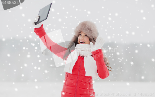 Image of woman in winter fur hat with tablet pc outdoors