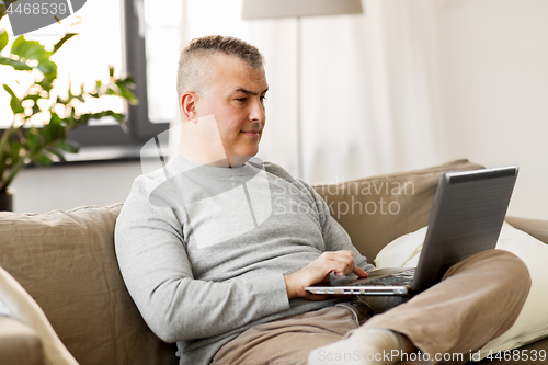 Image of man with laptop computer sitting on sofa at home