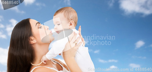 Image of mother kissing baby over sky background