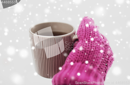 Image of close up of hand in winter mitten holding tea mug