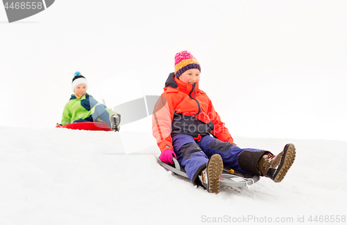 Image of happy kids sliding on sleds down hill in winter