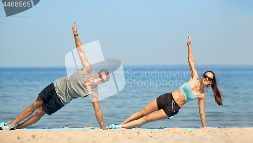 Image of couple doing side plank exercise on summer beach