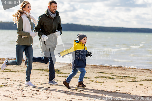 Image of happy family running along autumn beach