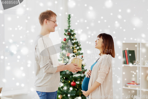 Image of husband giving christmas present to pregnant wife