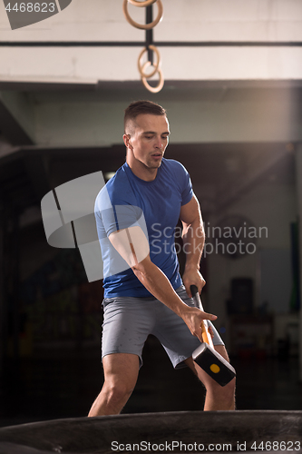 Image of man workout with hammer and tractor tire