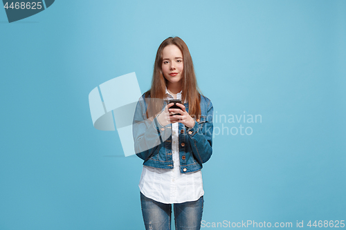 Image of The happy teen girl standing and smiling against blue background.