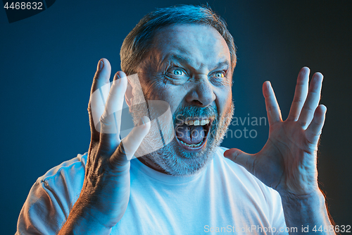 Image of The senior emotional angry man screaming on blue studio background