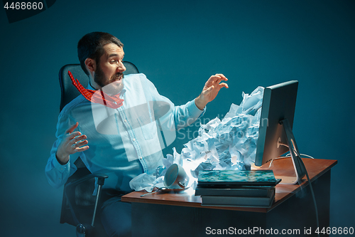 Image of Young stressed handsome businessman working at desk in modern office shouting at laptop screen and being angry about spam