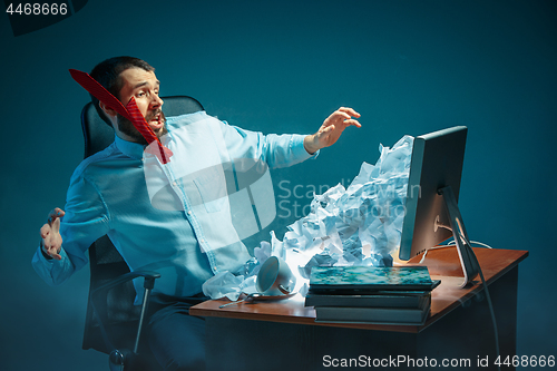 Image of Young stressed handsome businessman working at desk in modern office shouting at laptop screen and being angry about spam