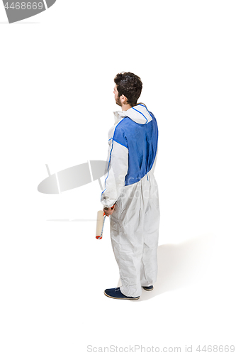 Image of Young male decorator painting with a paint roller climbed a ladder isolated on white background.