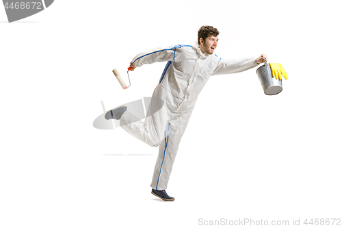 Image of Young male decorator painting with a paint roller climbed a ladder isolated on white background.