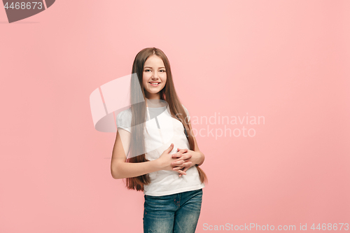 Image of The happy teen girl standing and smiling against pink background.