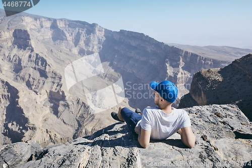 Image of Tourist resting on the edge of cliff