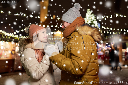 Image of happy couple holding hands at christmas market