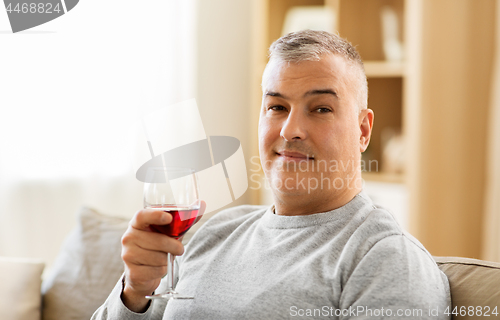 Image of man drinking red wine from glass at home