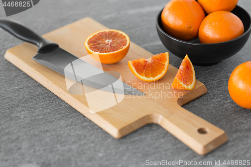 Image of close up of oranges and knife on cutting board