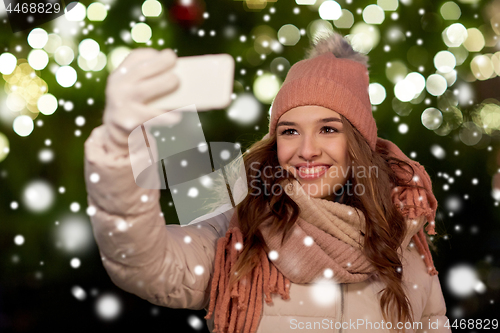 Image of young woman taking selfie over christmas tree
