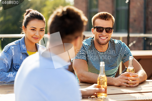 Image of happy friends with drinks at rooftop party