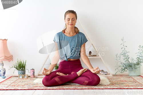 Image of woman meditating in lotus pose at yoga studio