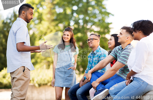 Image of happy international friends talking in park