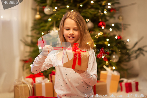 Image of smiling girl with christmas gift at home