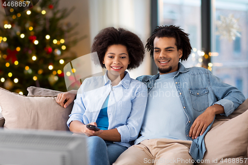 Image of happy couple watching tv at home on christmas