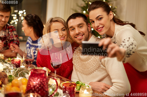 Image of friends having christmas dinner and taking selfie