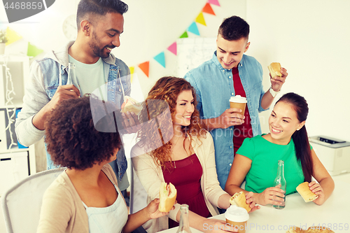 Image of happy friends or team eating at office party