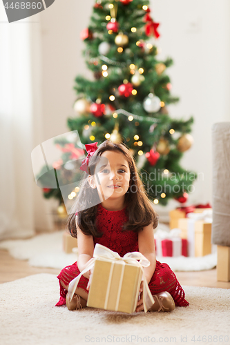 Image of happy girl with christmas gift at home