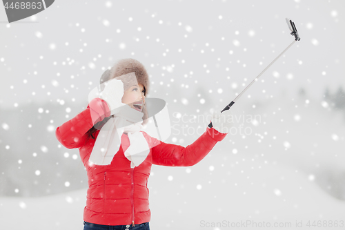 Image of happy woman with selfie stick outdoors in winter