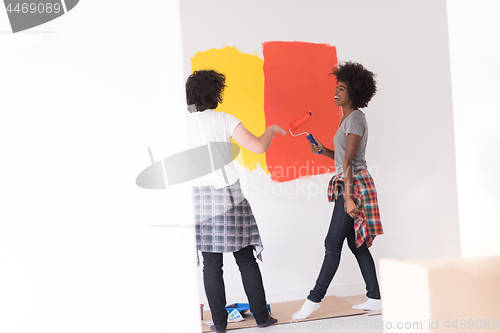 Image of multiethnic couple painting interior wall