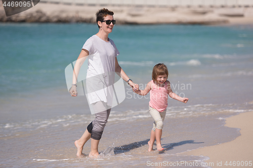 Image of mother and daughter running on the beach