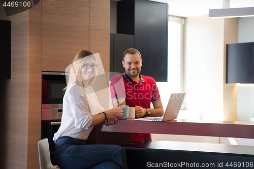 Image of couple drinking coffee and using laptop at home