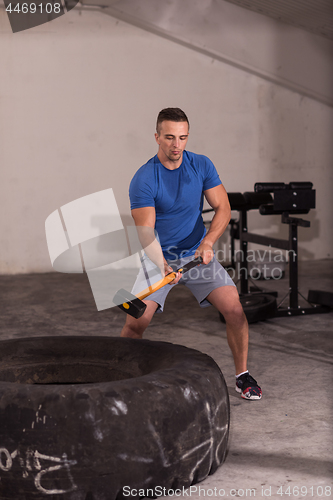 Image of man workout with hammer and tractor tire