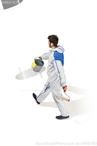 Image of Young male decorator painting with a paint roller climbed a ladder isolated on white background.