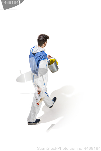 Image of Young male decorator painting with a paint roller climbed a ladder isolated on white background.