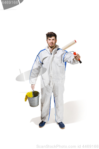 Image of Young male decorator painting with a paint roller climbed a ladder isolated on white background.