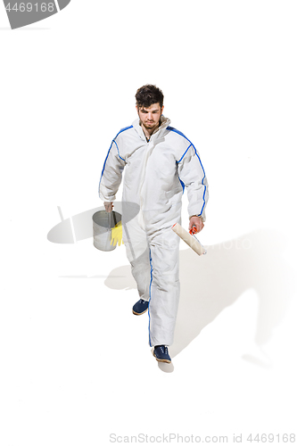 Image of Young male decorator painting with a paint roller climbed a ladder isolated on white background.