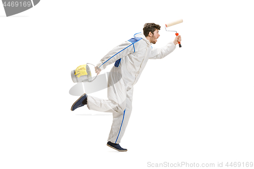 Image of Young male decorator painting with a paint roller climbed a ladder isolated on white background.