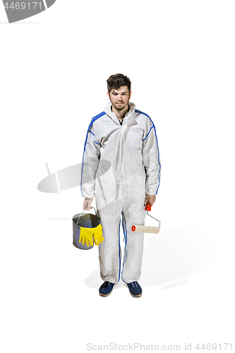 Image of Young male decorator painting with a paint roller climbed a ladder isolated on white background.