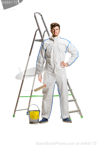 Image of Young male decorator painting with a paint roller climbed a ladder isolated on white background.