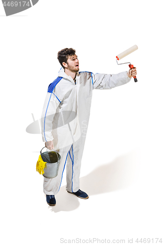 Image of Young male decorator painting with a paint roller climbed a ladder isolated on white background.