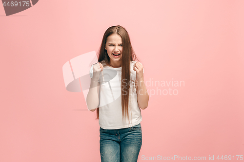 Image of Portrait of angry teen girl on a pink studio background