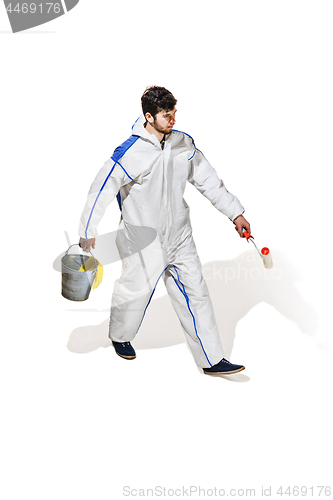 Image of Young male decorator painting with a paint roller climbed a ladder isolated on white background.