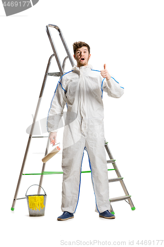 Image of Young male decorator painting with a paint roller climbed a ladder isolated on white background.