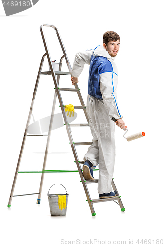 Image of Young male decorator painting with a paint roller climbed a ladder isolated on white background.