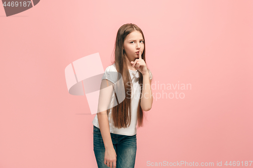 Image of The young teen girl whispering a secret behind her hand over pink background