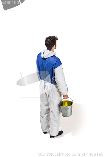 Image of Young male decorator painting with a paint roller climbed a ladder isolated on white background.