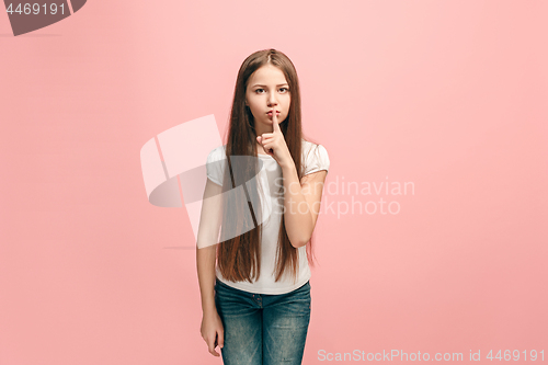 Image of The young teen girl whispering a secret behind her hand over pink background