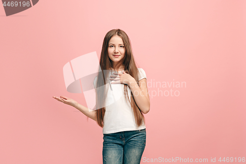 Image of The happy teen girl standing and smiling against pink background.